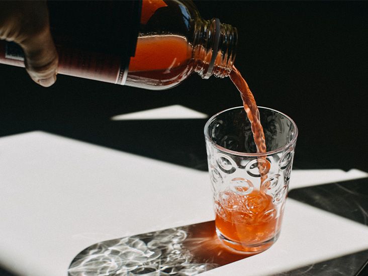 A person pouring a fizzy drink froma. glass bottle containing artificial sweeteners and food additives into a glass on a flat surface