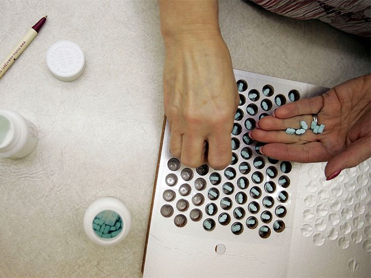 A pharmacy technician distributing pills to be packaged in a blister pack